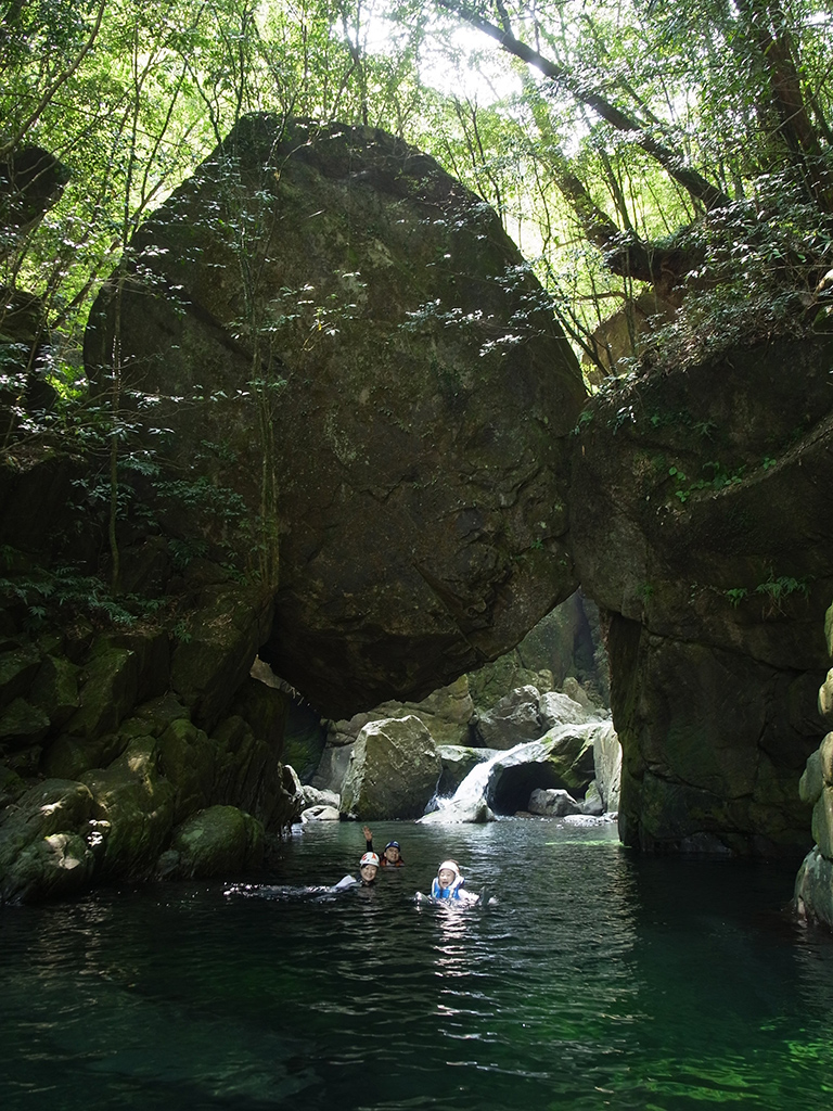 巨石が沢を塞ぎ、まるで巨大な石橋のようになっているポイントをみんなで泳いでいる写真