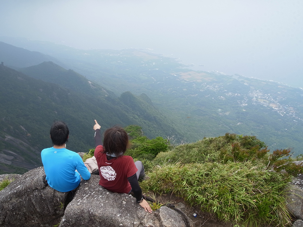 モッチョム岳山頂で雲が突然取れて、岩に腰掛け絶景を見渡すお二人の写真