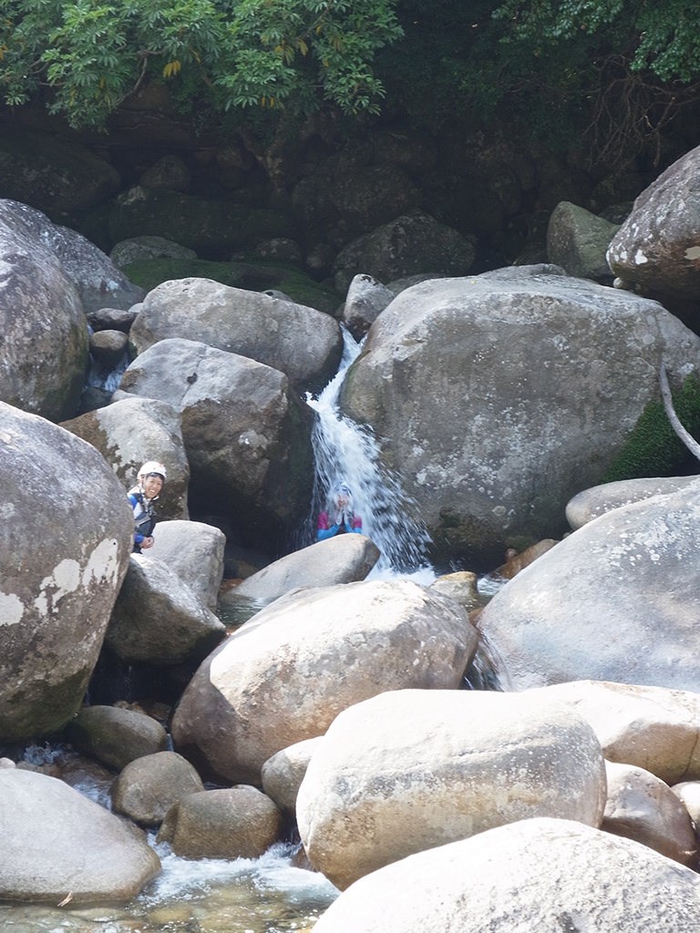 岩間から勢いよく出る水で滝行をしているNさんの写真
