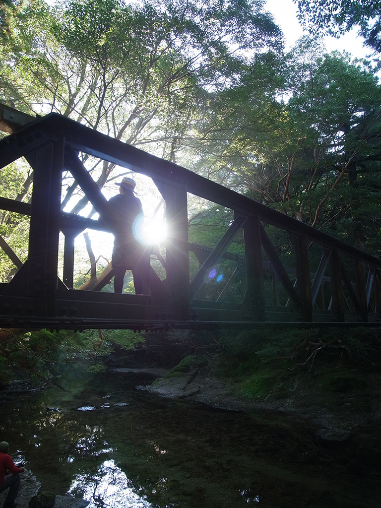 黒味岳に行く途中にある淀川に架かる橋の上にて朝陽を浴びる参加者の姿写真