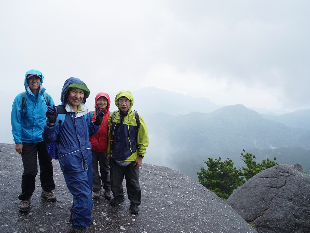 山頂から荒川ダム方面をバックにして、雲の切れ間を前に記念撮影