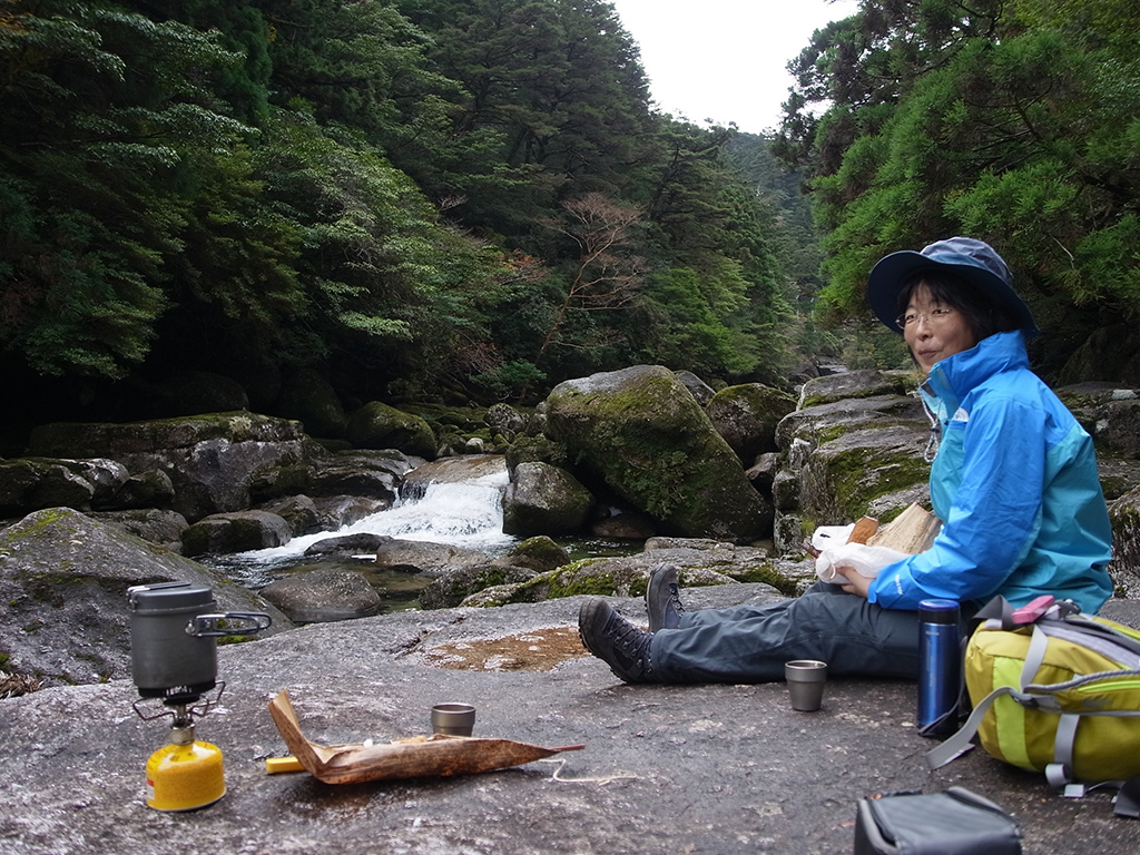 川原で竹皮に包まれたお弁当を広げて食べる参加者の写真