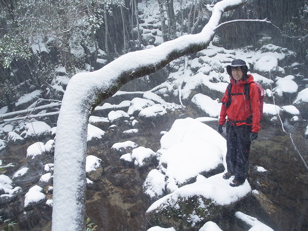 徒涉点で降りつける雪の中寒そうに立っている参加者の写真