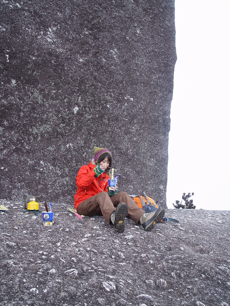 太忠岳山頂に鎮座する巨岩・天忠石の前でポーズを取る参加者Tさんの写真