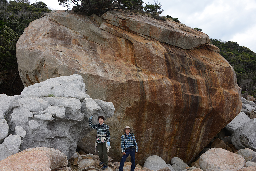 超巨大な花崗岩の巨石群の中に立ち尽くす二人の写真