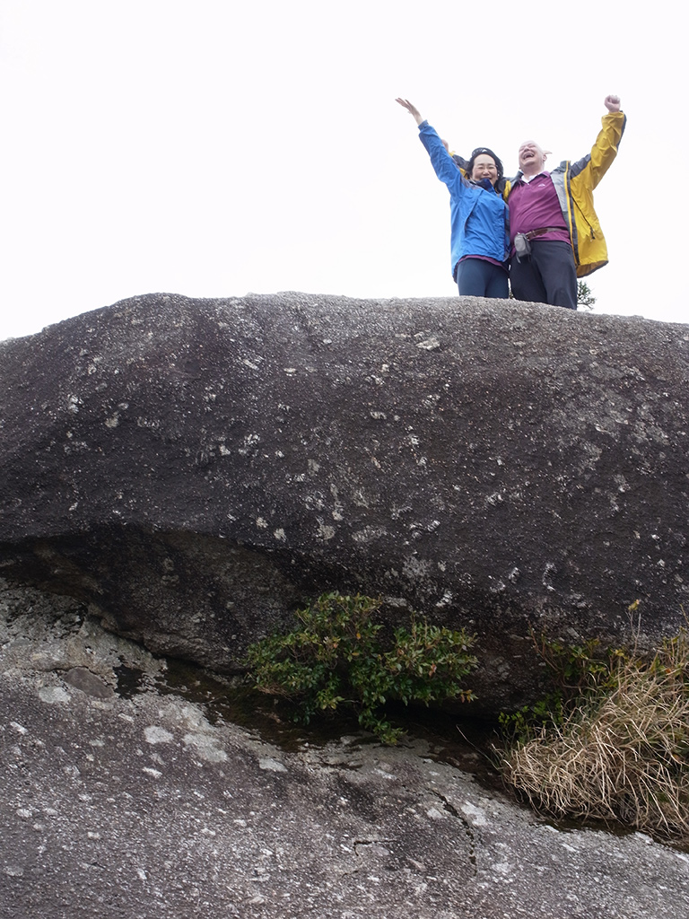 太鼓岩の上で、両腕を大きく広げて空を仰いでいる二人の写真