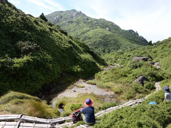 宮之浦岳を正面に眺められるポイントで、風を感じながら参加者二人と宮之浦岳を眺めている写真