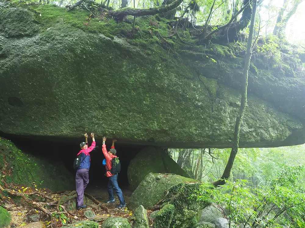 辻の岩屋と呼ばれる巨岩の下のスペースに入り、岩を支えているポーズを取る二人