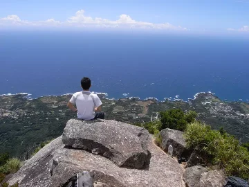 モッチョム岳の山頂で真っ青な海と水平線を眺めている男性の後ろ姿写真